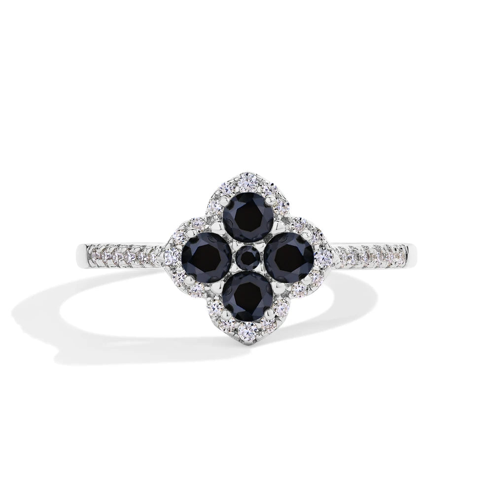 Ring with black gemstones and diamonds on a white background, branded with Mirrorquenn