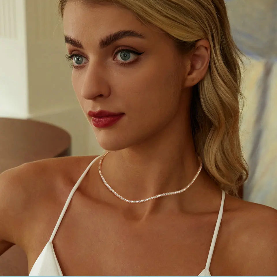 mirrorquenn Woman wearing a white necklace with a neutral background