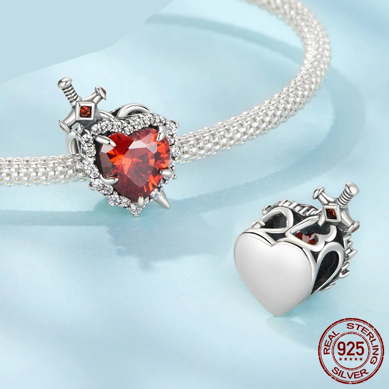 Heart-shaped silver and red gemstone charm on a light blue background with mirrorquenn branding.